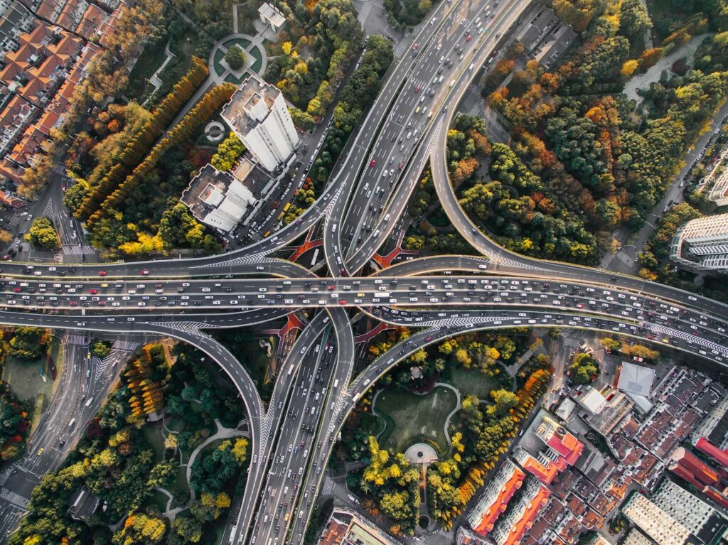 Aerial view of a freeway interchange with surround areas full of trees, greenery, and buildings